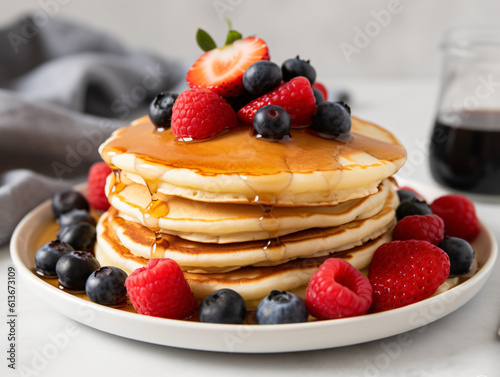 A stack of fluffy pancakes drizzled with maple syrup and topped with fresh berries.