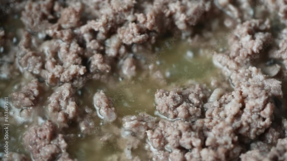 Cooking minced meat in hot iron skillet with wooden spoon, macro Cooking minced meat in hot iron skillet with wooden spoon, macro