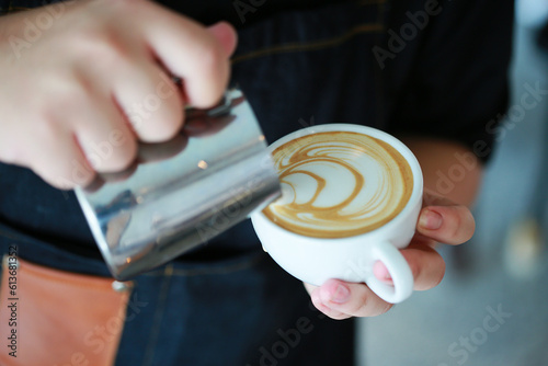 Barista hands pouring warm milk in coffee cup for making latte art. Multi skill of barista to make coffee drink in coffee shop. Profesional in hot and cold drink and ready to serve to the customer. photo
