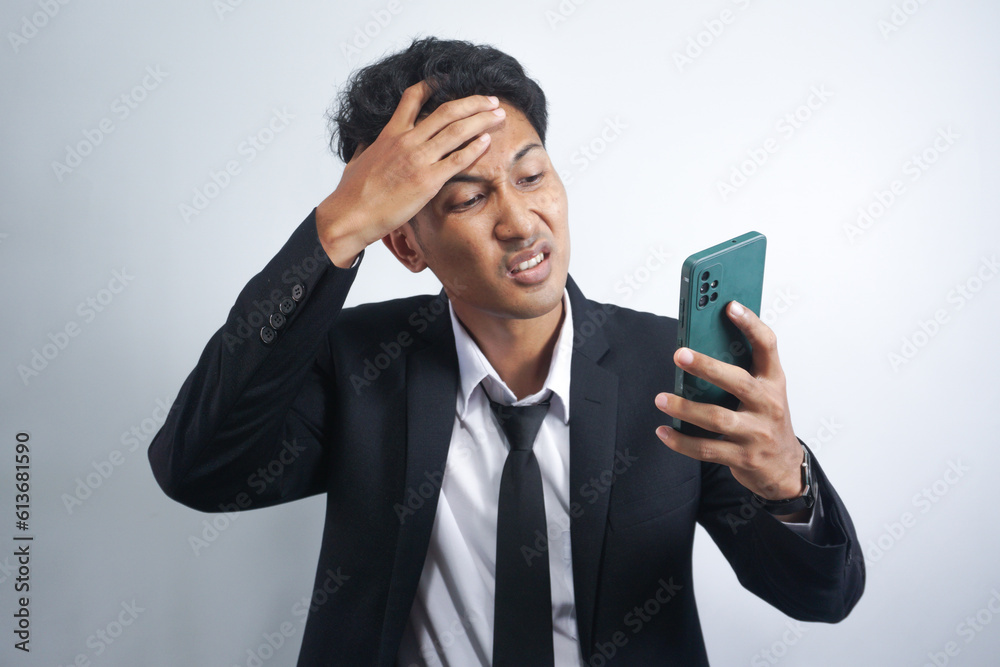 handsome young asian man wearing suit is angry and looking at cellphone handsome young asian man wearing suit is angry and looking at cellphone