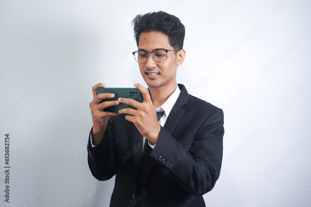Portrait of a passionate and serious young man in suit playing game on mobile in office isolated over white background Portrait of a passionate and serious young man in suit playing game on mobile in office isolated over white background