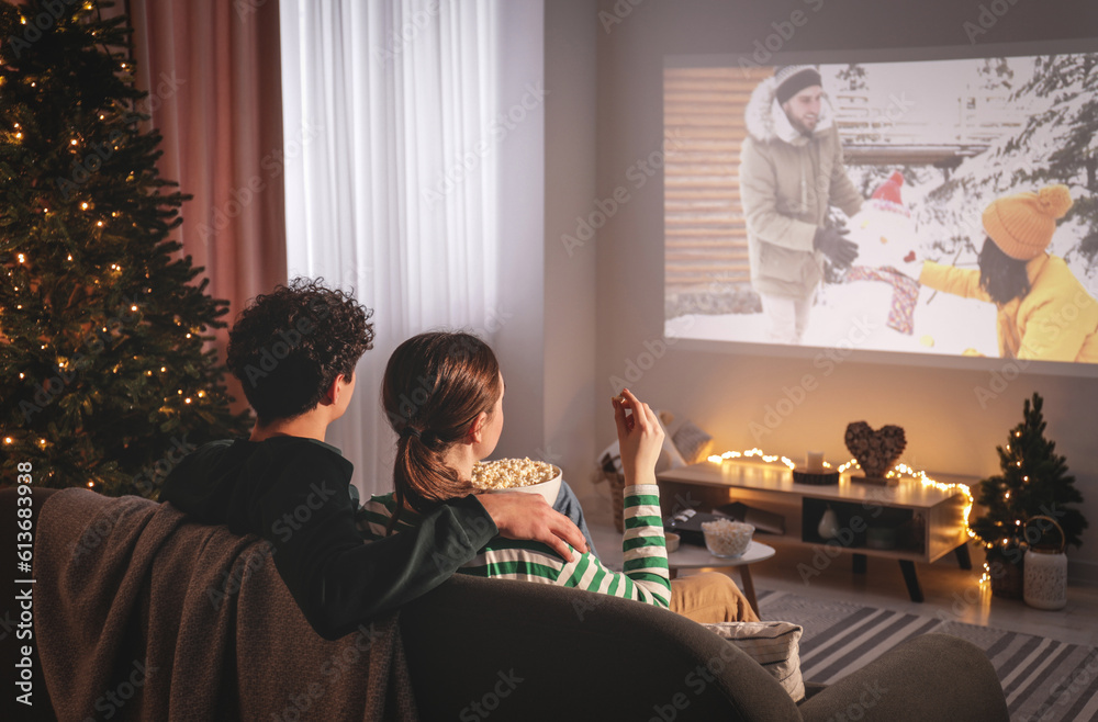 © New Africa - Couple watching romantic Christmas movie via video projector at home © New Africa - Couple watching romantic Christmas movie via video projector at home