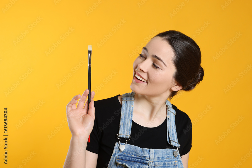 Woman with paintbrush on yellow background. Young artist Woman with paintbrush on yellow background. Young artist