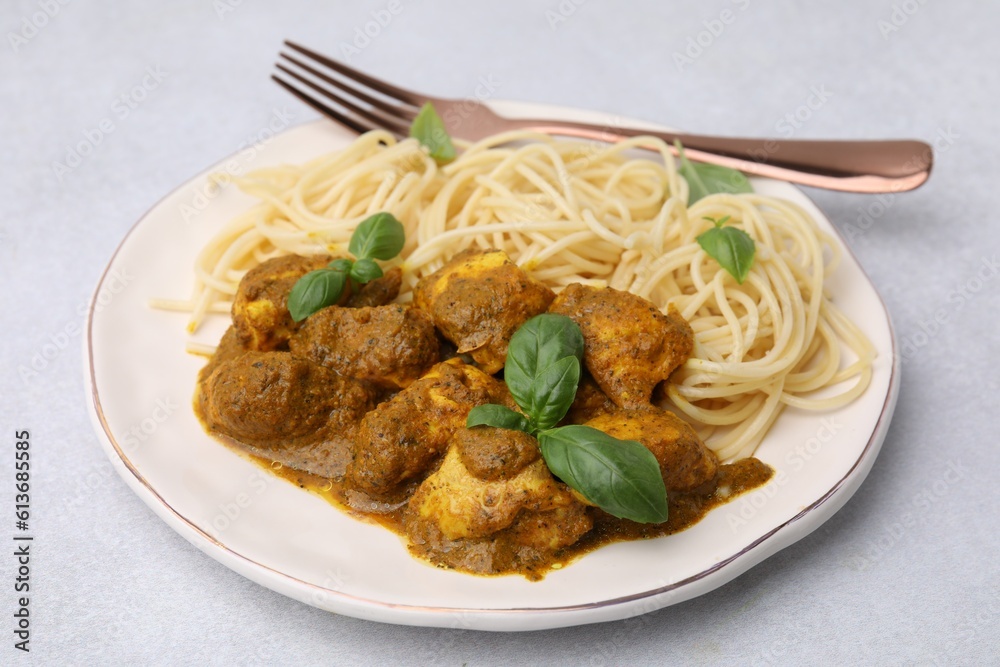 Delicious chicken, pasta with curry sauce and basil served on white table Delicious chicken, pasta with curry sauce and basil served on white table