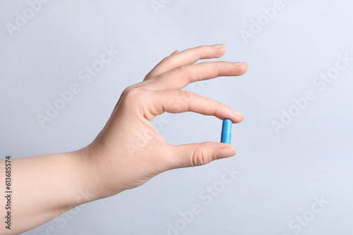 Woman with pill on light grey background  closeup