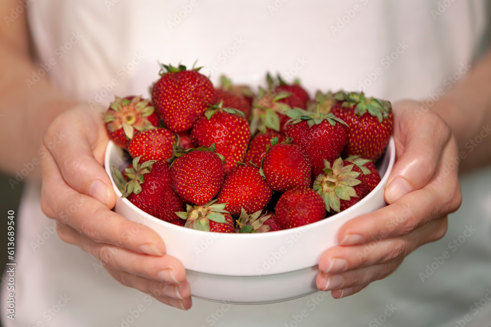 Girl holding a large bowl with delicious strawberries.