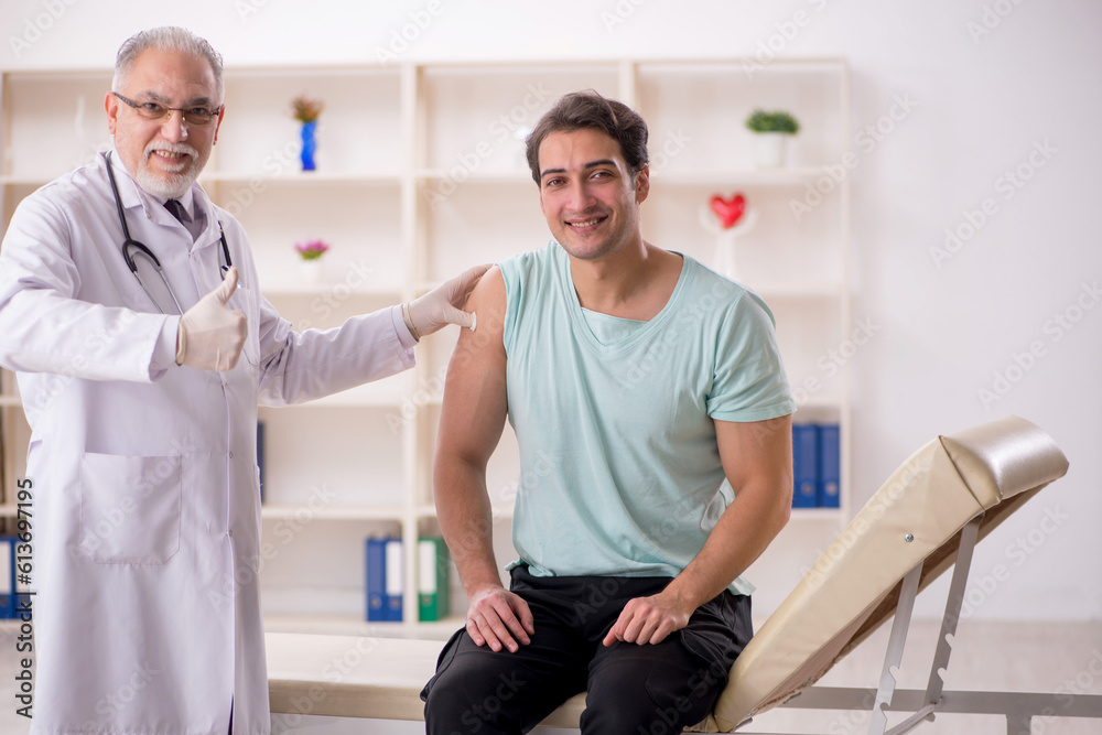 Obraz premium Young male patient visiting old male doctor in vaccination conce