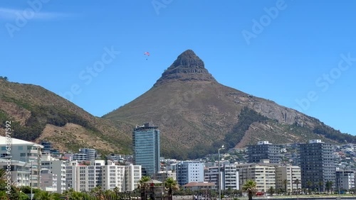 Paragliding hang glide flying off Table Mountain Lions Head downtown city skyscraper buildings to Cape Town beach South Africa summer adventure beautiful calm wind still morning  slow motion follow
