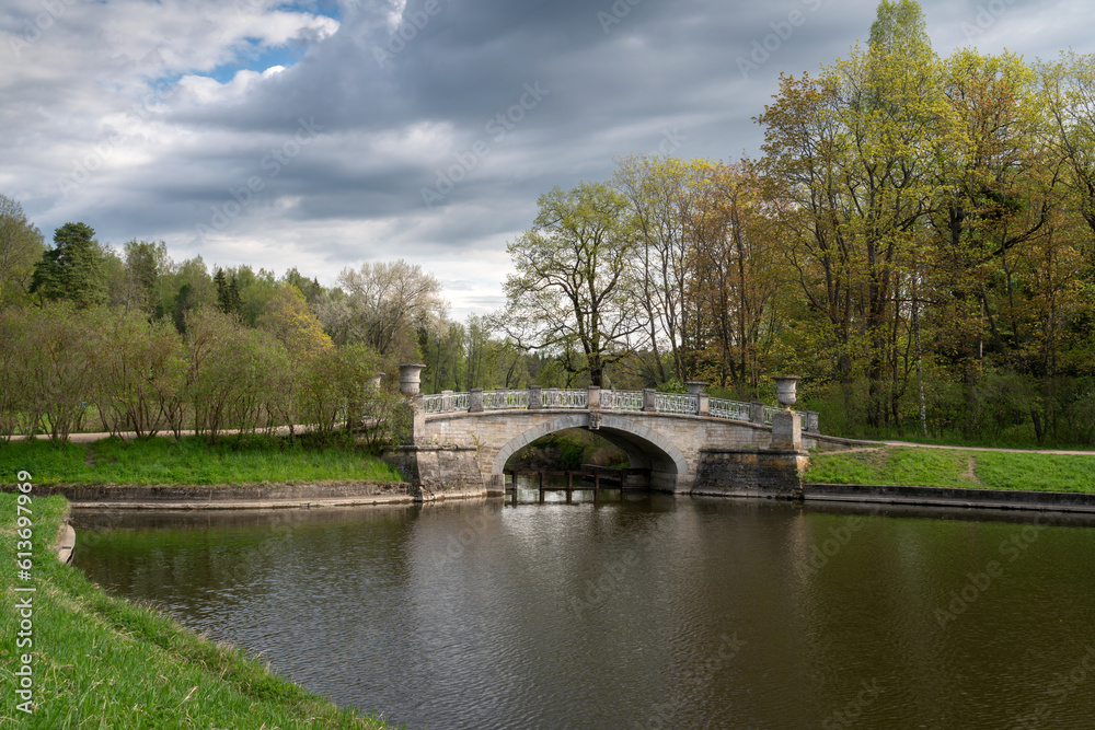 View of the Slavyanka River and the Viscontiev Bridge in the Pavlovsk Palace and Park Complex on a sunny spring day, Pavlovsk, Saint Petersburg, Russia