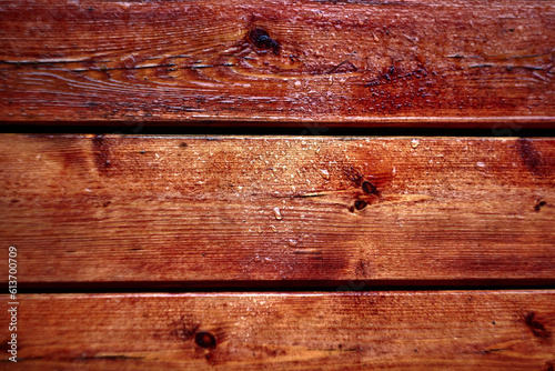 Boards with texture covered with red varnish in the rain