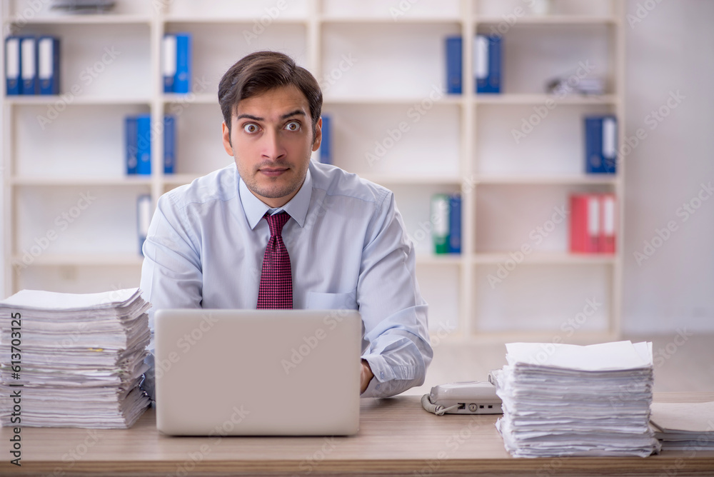 Young male employee and too much work in the office Young male employee and too much work in the office
