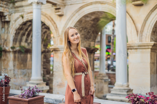 Happy female tourist traveler discover interesting places and popular attractions and walks in the old city of Antalya. Hadrian Kapisi turkey landmark city history. Popular tourist attraction - photo