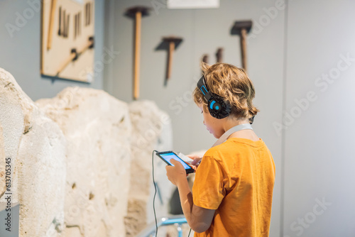 Boy looking at sculptures and listening to audio guide at museum exhibition