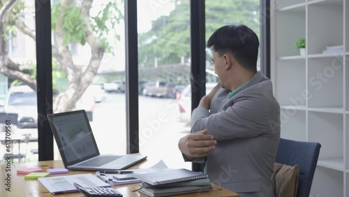 Asian business man Sitting working on laptop with office syndrome problem back and shoulder pain Try stretching to relieve wrist pain. working too long