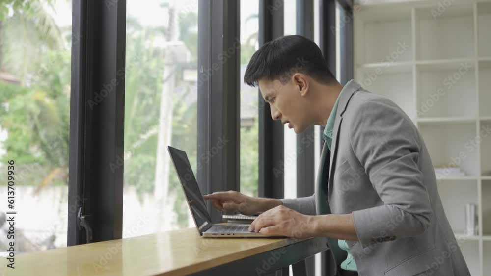 Asian male businessman working in the office calculate financial reports Manage documents using your laptop and calculator as an aid. in the concept of financial accounting Asian male businessman working in the office calculate financial reports Manage documents using your laptop and calculator as an aid. in the concept of financial accounting