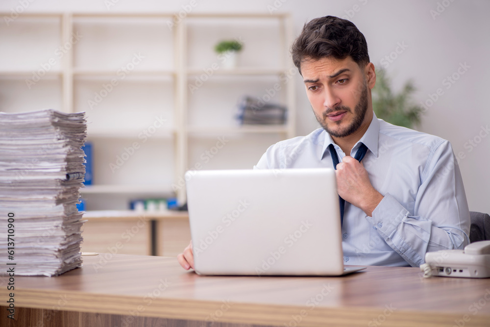 Young male employee and too much work in the office Young male employee and too much work in the office