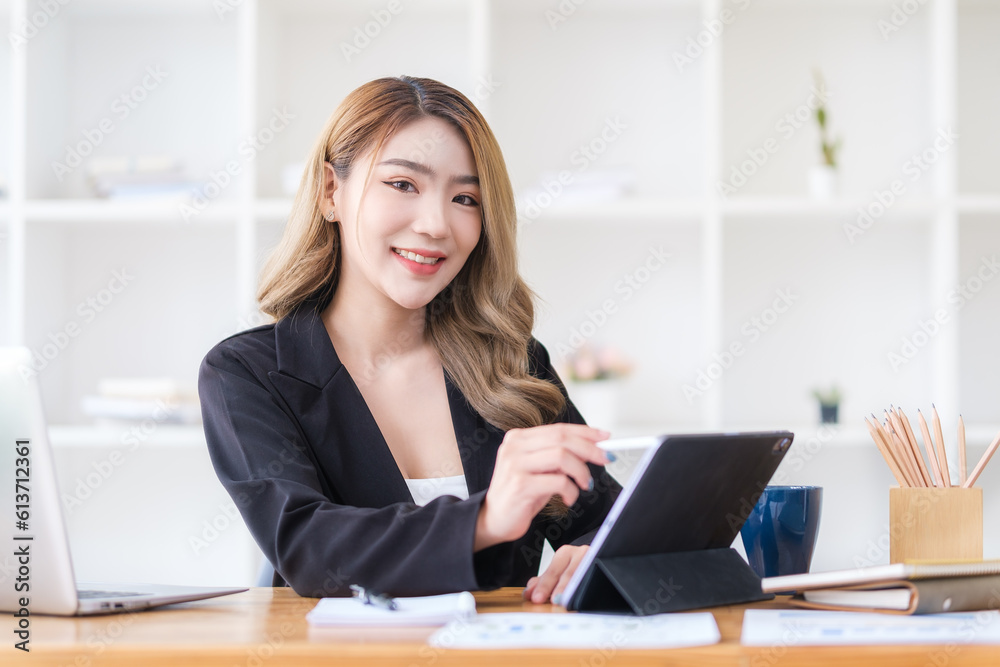 Charming millennial female manager using digital tablet at her workstation. Charming millennial female manager using digital tablet at her workstation.