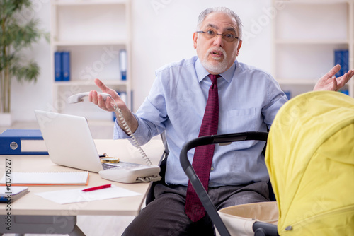 Old male employee looking after new born at workplace