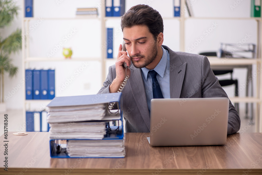 Young male employee and too much work in the office Young male employee and too much work in the office