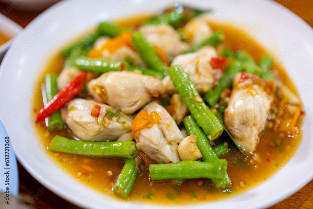 Stir-fried crab meat with yellow pepper and long beans in a white dish on the table.