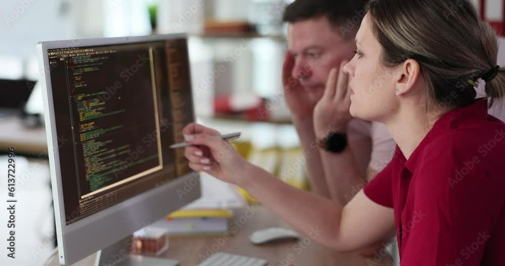 A woman and a man are looking at the code on the computer screen, close-up. Testing a software application