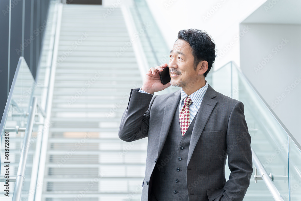 オフィスでスマホで話す中年ビジネスマン(上司・社長・リーダー) オフィスでスマホで話す中年ビジネスマン(上司・社長・リーダー)