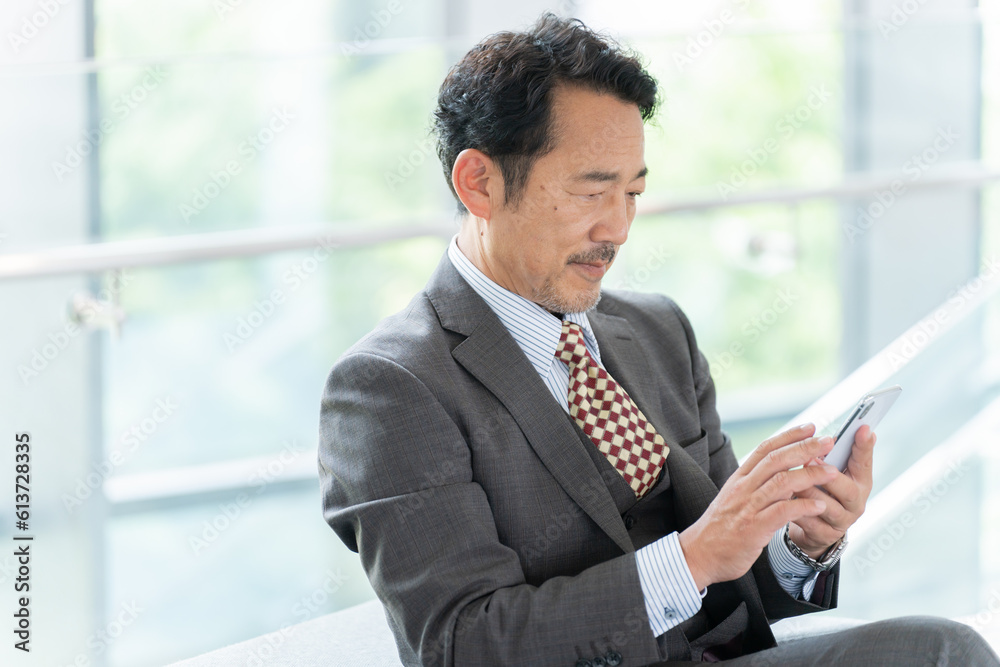 オフィスでスマホを使う中年ビジネスマン（上司・社長・リーダー）