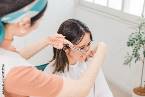 美容室に来た女性と髪を切る・カットする美容師・理容師の女性 