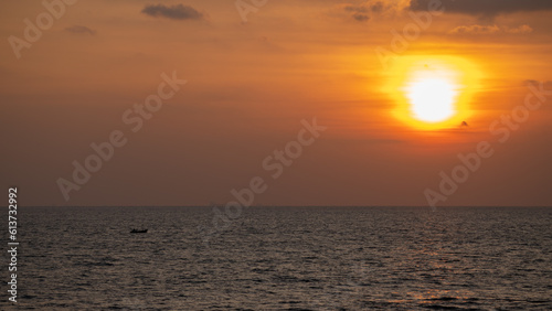 Sunset on the horizon  a small fishing boat traveling alone.