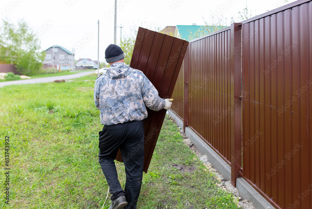 Workers install a metal profile fence