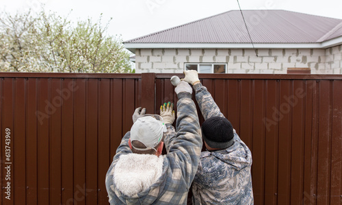 Workers install a metal profile fence