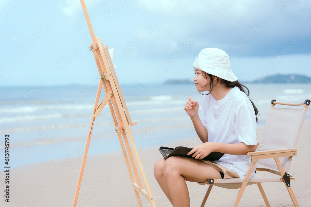 Asian girl painting in watercolor on the beach