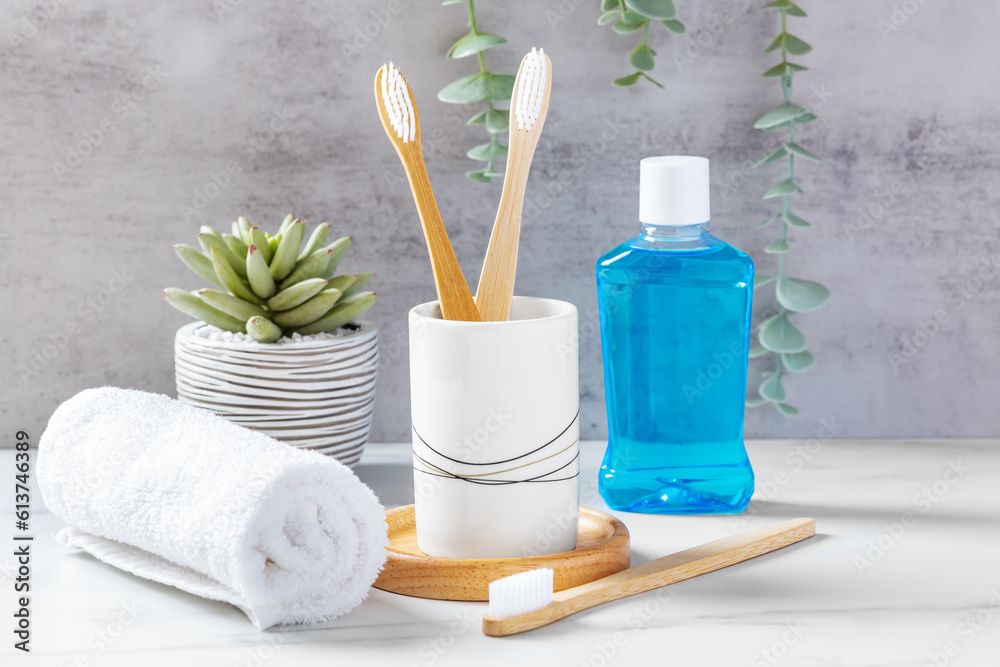 Dental health care and oral hygiene concept, bamboo toothbrushes in cup with mouthwash and towel - obrazy, fototapety, plakaty 