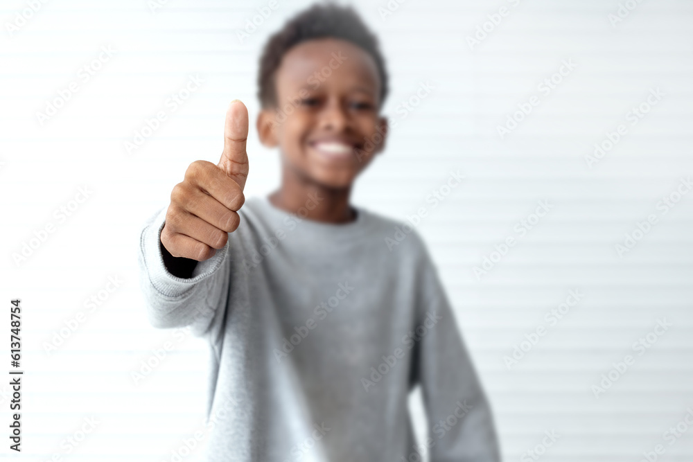 African boy showing thumb up on white background, selective focus African boy showing thumb up on white background, selective focus