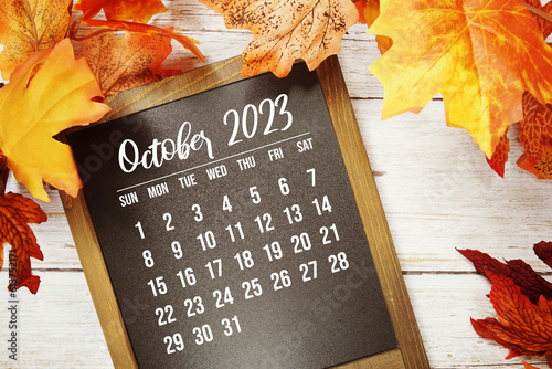 October 2023 monthly calendar with maple leaf on wooden background