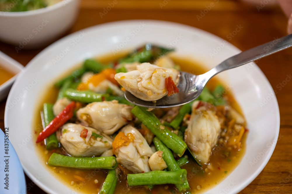 The spoon was scooping up fried crabmeat with yellow pepper and long bean from the plate. The spoon was scooping up fried crabmeat with yellow pepper and long bean from the plate.