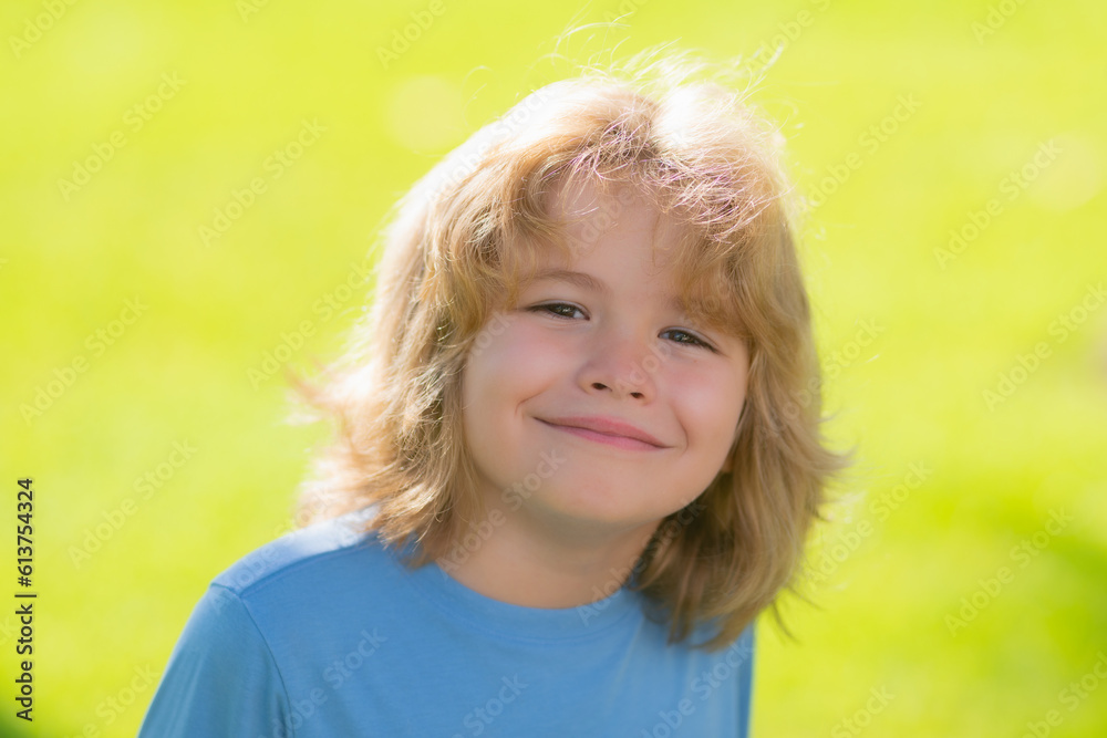 Funny kids emotions. Outdoor close up portrait of a cute little child playing outdoor. Cute funny blonde little child close up portrait on green grass background. Funny kids emotions. Outdoor close up portrait of a cute little child playing outdoor. Cute funny blonde little child close up portrait on green grass background.