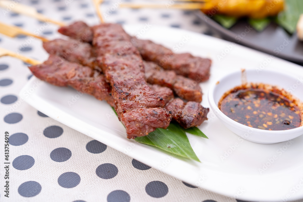 Skewered grilled beef served in a white plate with Thai Spicy Sauce. Skewered grilled beef served in a white plate with Thai Spicy Sauce.