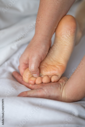 Close-up of man doing foot massage on white background. Reflexology foot massage. Tired feet concept. Vertical