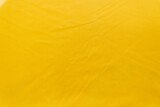 Bright yellow syntetic fabric with folds as a texture, pattern, background
