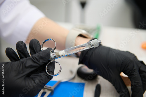 Close-up medical syringe with cartridge of dental anesthetic in hands of a dentist  preparing anelgesic injection por painless teeth treatment in dentistry clinic. Orthodontics. Maxillofacial surgery