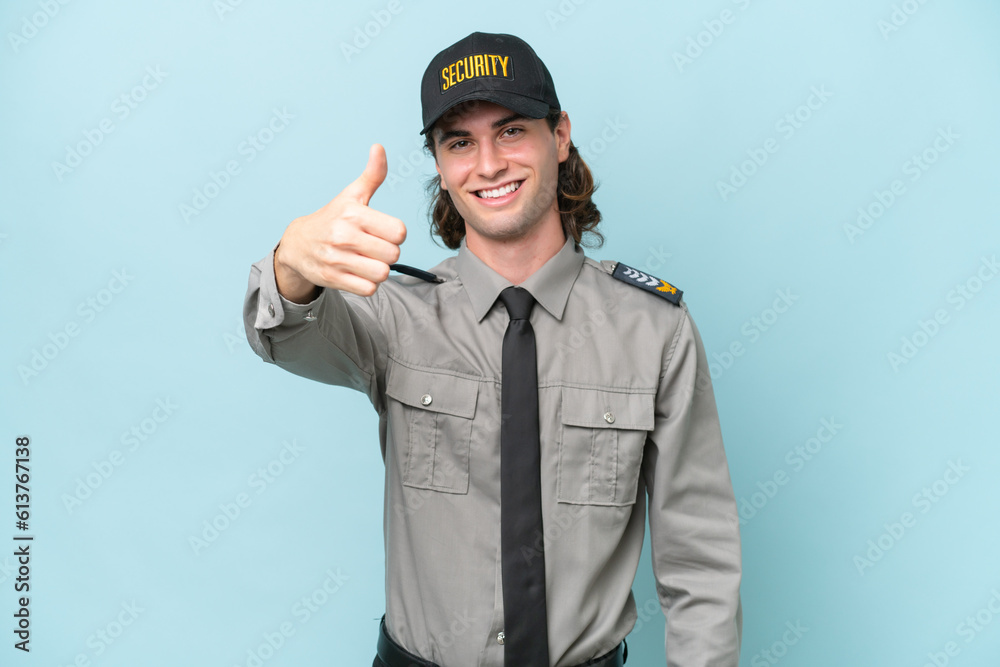 Young safeguard man isolated on blue background with thumbs up because something good has happened Young safeguard man isolated on blue background with thumbs up because something good has happened