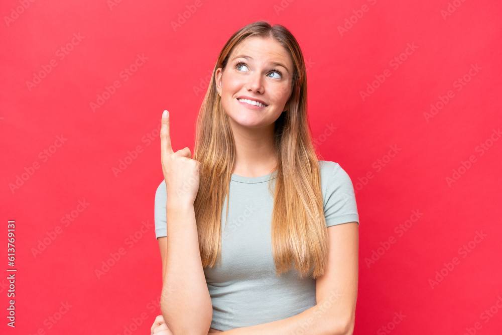 Young beautiful woman isolated on red background pointing up a great idea Young beautiful woman isolated on red background pointing up a great idea