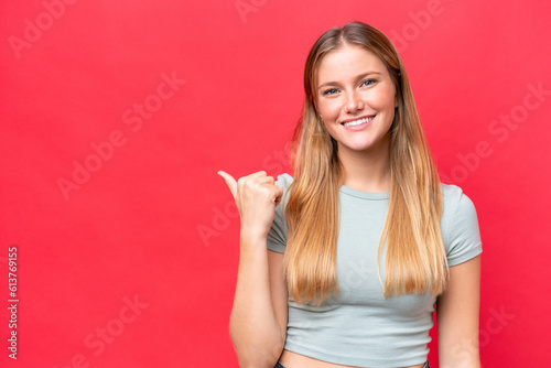 Young beautiful woman isolated on red background pointing to the side to present a product