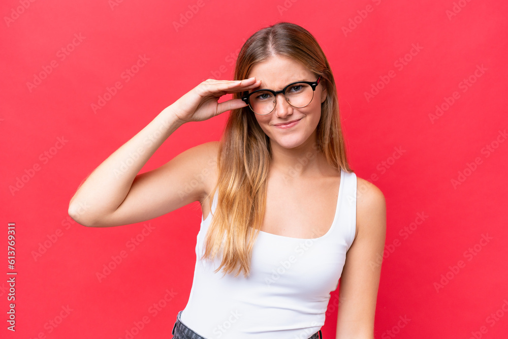 Young beautiful woman isolated on red background looking far away with hand to look something Young beautiful woman isolated on red background looking far away with hand to look something