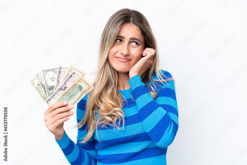 Young Uruguayan woman taking a lot of money isolated on white background frustrated and covering ears Young Uruguayan woman taking a lot of money isolated on white background frustrated and covering ears