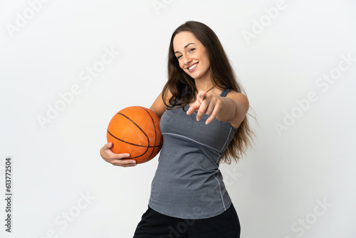 Young woman playing basketball over isolated white background pointing front with happy expression