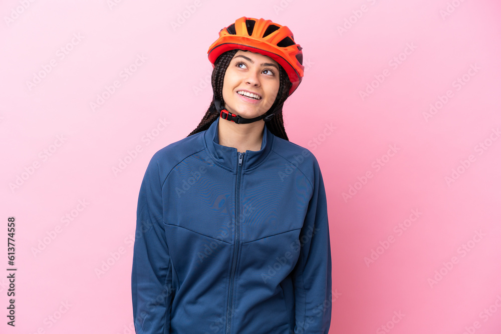 Fototapeta premium Teenager cyclist girl isolated on pink background thinking an idea while looking up