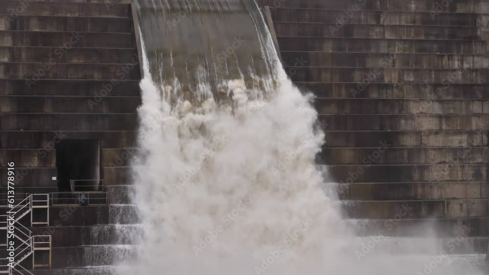 Medium handheld shot of Hinze Dam under heavy rain and water overflow