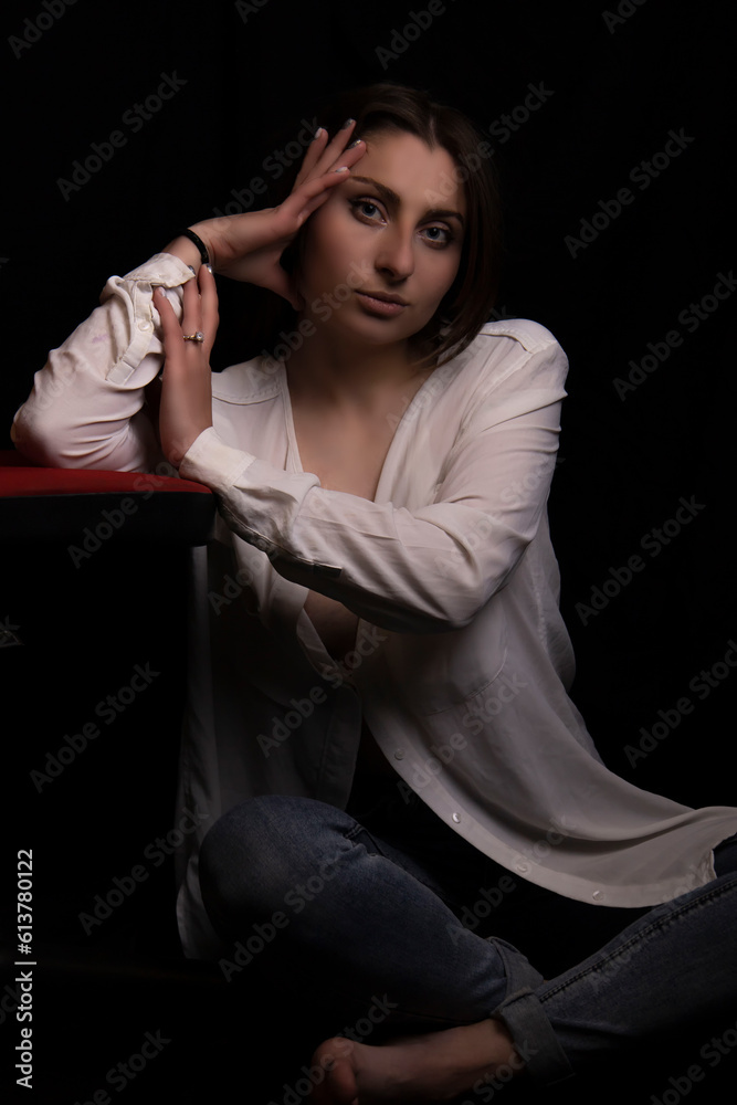 Beautiful young girl in a white shirt and jeans on a black background Beautiful young girl in a white shirt and jeans on a black background